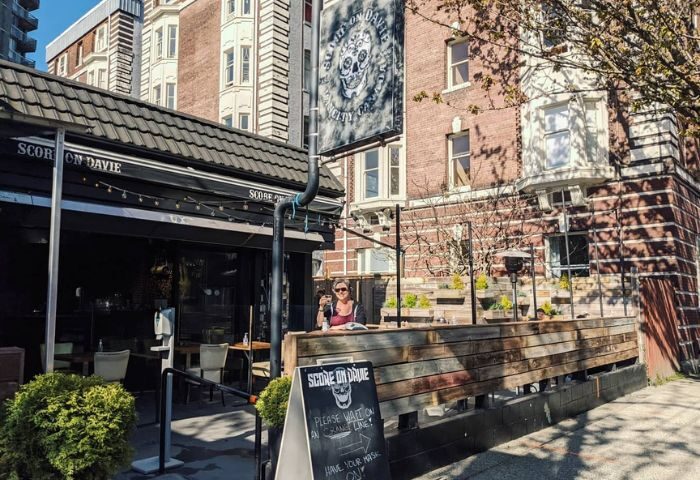 Score on Davie Sports Bar in Vancouver, a popular gay bar. Outdoor patio with a woman enjoying a drink. Davie Village gay scene.