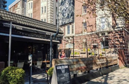 Score on Davie Sports Bar in Vancouver, a popular gay bar. Outdoor patio with a woman enjoying a drink. Davie Village gay scene.