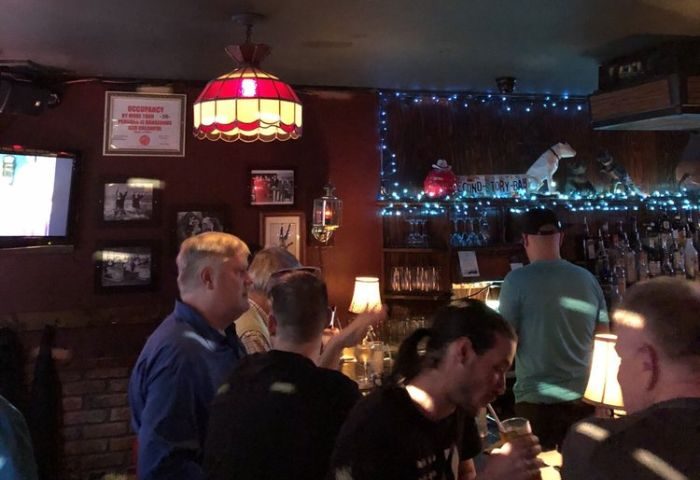 Second Story Bar gay night party in Chicago. Interior shot of patrons at the bar, warm lighting, and a lively atmosphere. Gay travel.