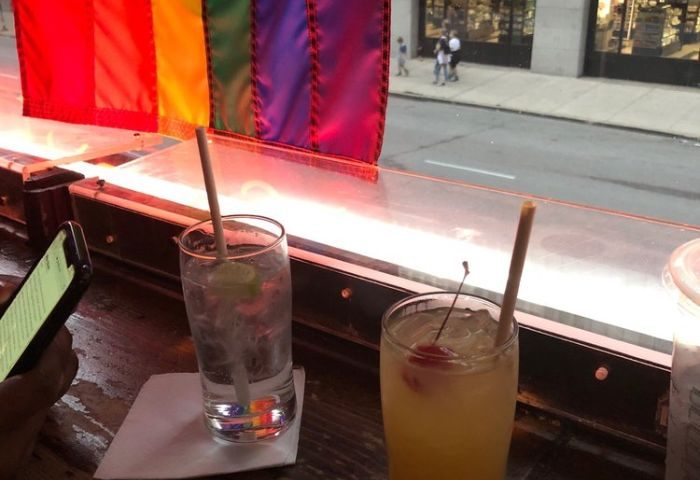 Chicago gay night party at a second-story bar. Cocktails with rainbow flag. Gay travel advice for best bars and nightlife in Chicago.