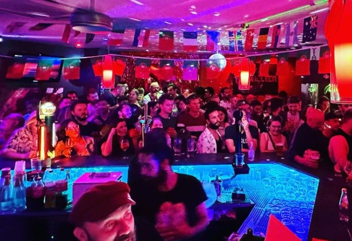 Shelter Bar in Lisboa. Crowded gay bar with flags, disco ball, and blue-lit bar. Gay travel advice, nightlife, and bar scene.