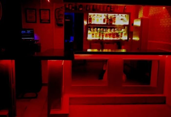 Bar area at a gay cruise club in Madrid. Red lighting, bottles on shelves. Gay travel destination for men.