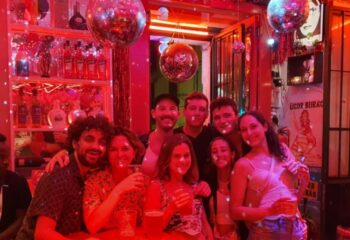 Group enjoying Lisbon's Side Bar, a gay-friendly travel destination. Disco balls, red lighting, and drinks create a vibrant atmosphere.