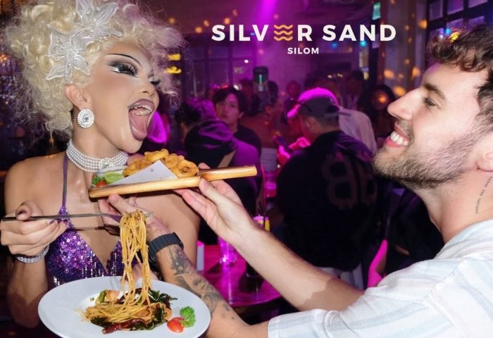 Silver Sand Silom gay bar Bangkok: Drag queen eating food served by a man. A popular gay nightlife destination in Silom, Thailand.