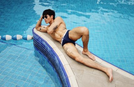 Man at voco Orchard Singapore pool. Muscular build, tattoos, sunglasses, swim briefs. Gay travel. Huang-1.jpg. IHG Hotel.