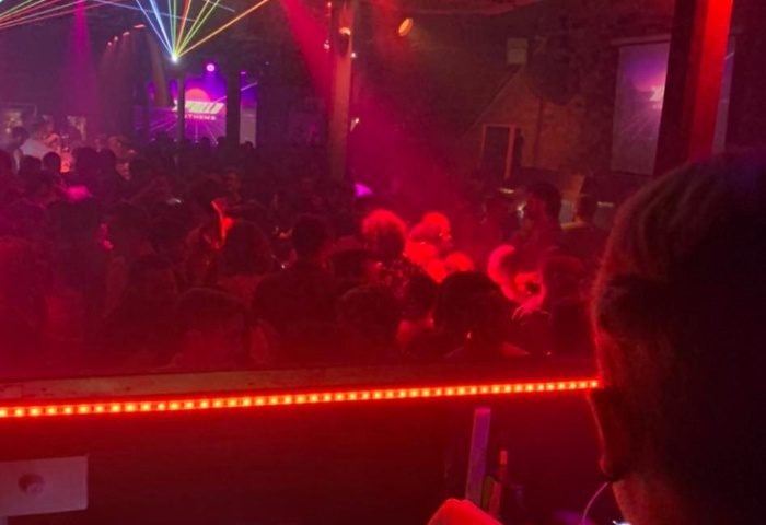 Crowd at Sircuit Bar, Melbourne. Gay bar scene with laser lights and people dancing. Nightlife for gay men in Australia. Red lighting.