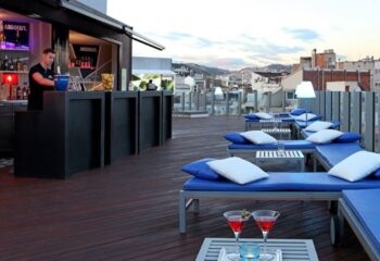 Sky Bar at Axel Hotel, a gay bar in Barcelona. Rooftop lounge area with bar, city views, lounge chairs, and cocktails. Gay travel.