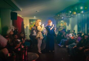 Drag queens perform at Sky Bar, Axel Hotel, a gay bar in Barcelona. Patrons watch the show in a stylish, festive atmosphere.