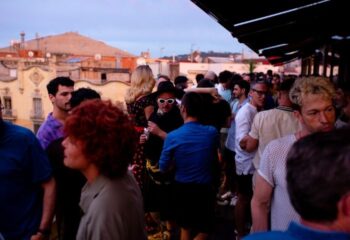 Sky Bar at Axel Hotel, a gay bar in Barcelona. Crowd of people socializing on a rooftop with city views. Gay travel in Barcelona.