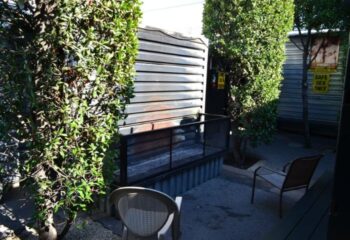 Slammer outdoor area. Grilling area with chairs, trees, and Safe Sex Only sign. Gay travel destination, providing a safe and welcoming space.