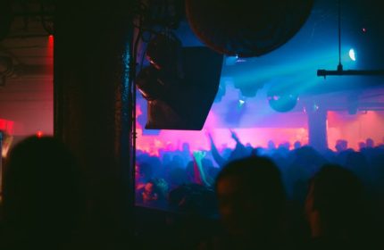 Smartbar gay party in Chicago. A crowd dances under blue and pink lights, with disco balls and speakers visible. Nightlife scene.