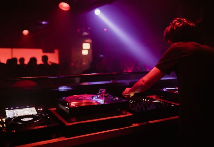 Smartbar Chicago gay party: DJ mixing music at a crowded dance club. Nightlife scene with colorful lights and vibrant energy.