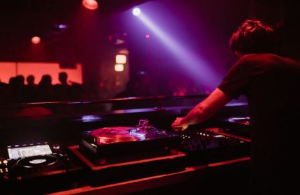 Smartbar Chicago gay party: DJ mixing music at a crowded dance club. Nightlife scene with colorful lights and vibrant energy.