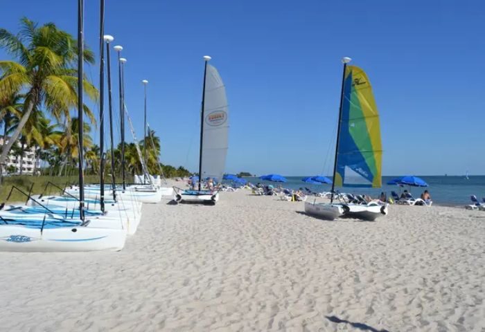 Smathers Beach in Key West: Sailboats line the shore of a popular beach. Gay cruise visitors enjoy the sun and sand on a clear day.