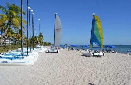Smathers Beach in Key West: Sailboats line the shore of a popular beach. Gay cruise visitors enjoy the sun and sand on a clear day.