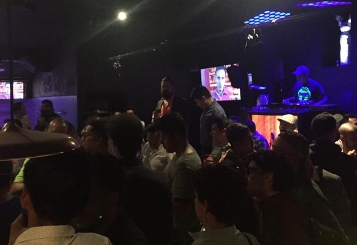 Inside Sodome Bath House: A crowded scene at the gay bathhouse, with a DJ playing music and men socializing in a dimly lit space.