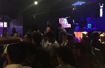 Inside Sodome Bath House: A crowded scene at the gay bathhouse, with a DJ playing music and men socializing in a dimly lit space.