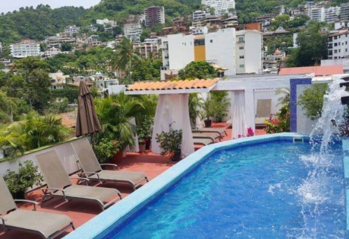 Rooftop pool at Spartacus Gay Sauna in Puerto Vallarta. Lounge chairs, cabana, city view. Gay travel destination.