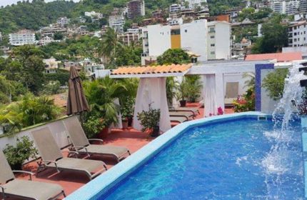Rooftop pool at Spartacus Gay Sauna in Puerto Vallarta. Lounge chairs, cabana, city view. Gay travel destination.