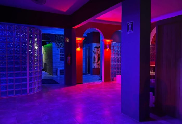 Interior of Spartacus gay sauna in Puerto Vallarta, featuring red and blue lighting, glass block walls, and arched doorways.