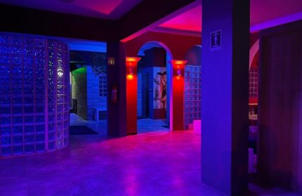 Interior of Spartacus gay sauna in Puerto Vallarta, featuring red and blue lighting, glass block walls, and arched doorways.