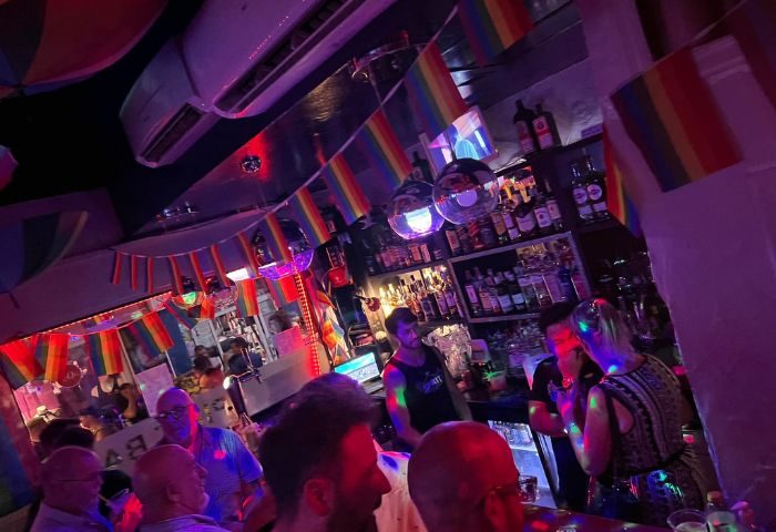Inside Spirit Bar, a gay bar and party venue in Benidorm. Rainbow flags, disco balls, and people enjoying the vibrant atmosphere.