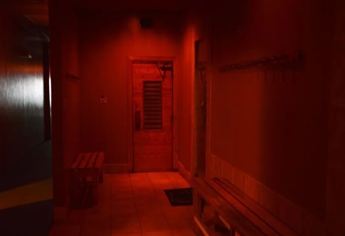 Red-lit sauna interior at Splash, a gay cruising spot in Toronto. Bench seating and the sauna door are visible. Steam and sauna experience.