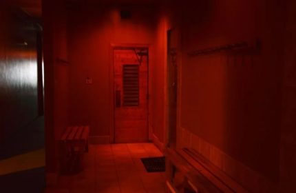 Red-lit sauna interior at Splash, a gay cruising spot in Toronto. Bench seating and the sauna door are visible. Steam and sauna experience.