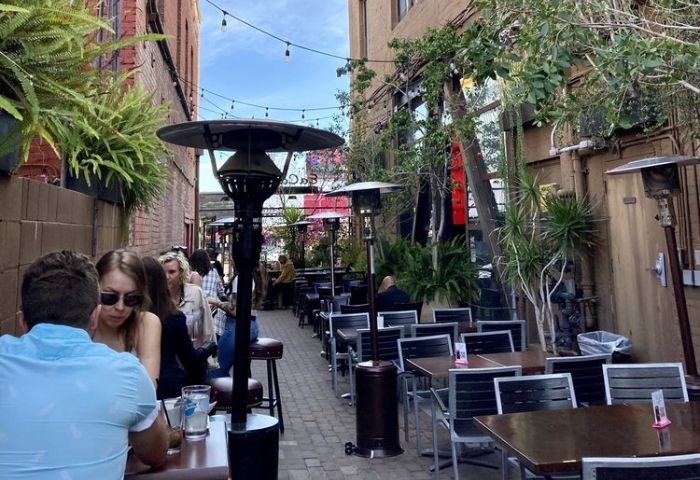 St Felix Hollywood outdoor patio. Tables and chairs line a narrow alleyway, with heaters and greenery. Popular gay-friendly spot.
