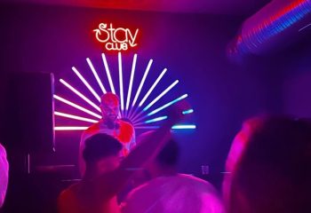 Inside Stay Club Istanbul: DJ performs amid neon lights, drawing a crowd. Nightlife for gay men's travel, creating a vibrant atmosphere.