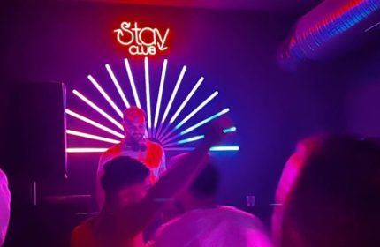 Inside Stay Club Istanbul: DJ performs amid neon lights, drawing a crowd. Nightlife for gay men's travel, creating a vibrant atmosphere.