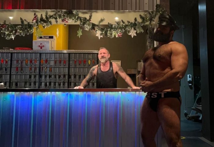 Steamworks Vancouver's gay sauna: Two men at the counter, one in leather cap and jockstrap. Gay travel advice in Vancouver.