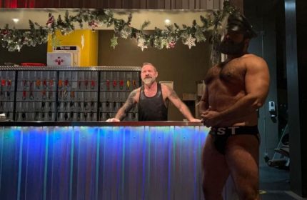 Steamworks Vancouver's gay sauna: Two men at the counter, one in leather cap and jockstrap. Gay travel advice in Vancouver.