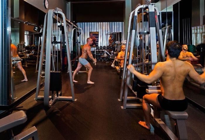 Steamworks Vancouver gym. Gay sauna in Vancouver with men working out on weight machines, shirtless, in shorts. Gay travel.