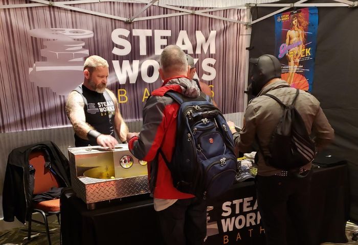 Steamworks Baths booth at a gay event in Vancouver. A man is serving customers at the Steamworks gay sauna stand.