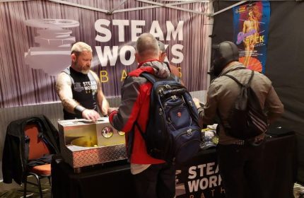 Steamworks Baths booth at a gay event in Vancouver. A man is serving customers at the Steamworks gay sauna stand.