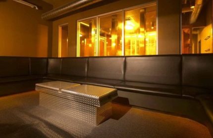 Interior of Steamworks Toronto, a gay bathhouse. Features a black leather couch and a metal coffee table.