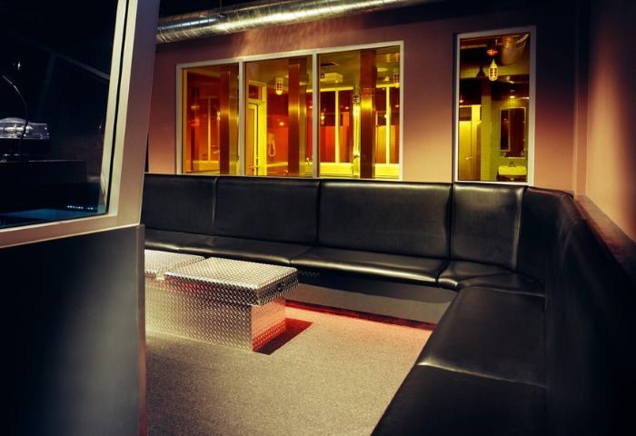 Steamworks Toronto interior. Lounge area with black leather seating, metal tables, and views into the bathhouse. Gay travel.