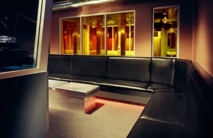 Steamworks Toronto interior. Lounge area with black leather seating, metal tables, and views into the bathhouse. Gay travel.