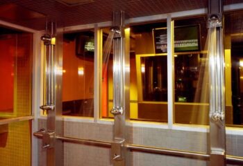 Showers at Steamworks Toronto, a popular gay sauna. Stainless steel fixtures, tiled walls, and glass partitions create a sleek, modern spa.
