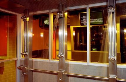 Showers at Steamworks Toronto, a popular gay sauna. Stainless steel fixtures, tiled walls, and glass partitions create a sleek, modern spa.