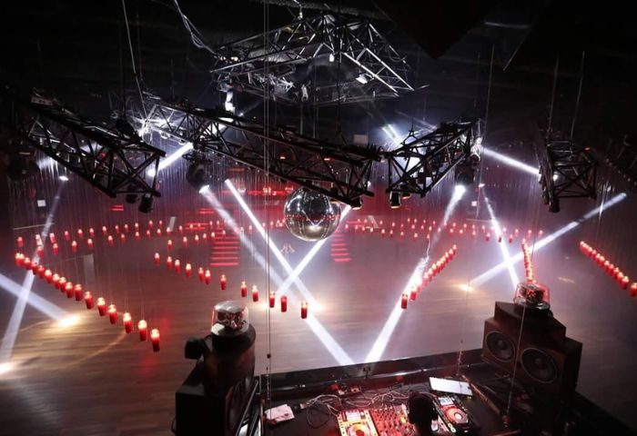 Stereo Bar gay party in Montreal. Interior view of a nightclub with lights, disco ball, DJ equipment, and red candles hanging from the ceiling.