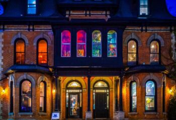 Storm Crow Manor in Toronto, Canada. Brick building with colorful stained glass windows. Gay travel destination for unique dining.