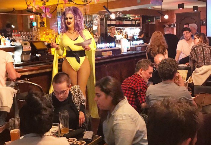 Street 66 gay bar, Dublin. Drag queen in yellow costume performing in front of a crowd. Gay travel advice, nightlife, pub.