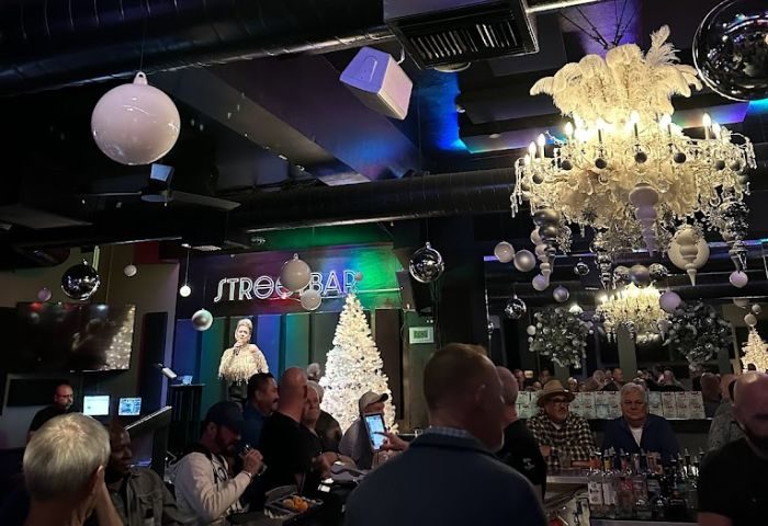 Streetbar-Dine: Gay bar interior, chandeliers, and Christmas decor. Men gather at the bar, enjoying the ambiance and social scene.