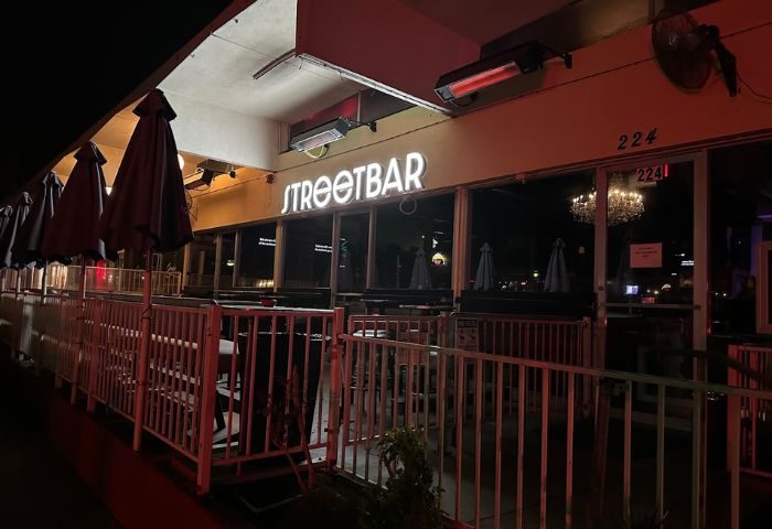 Streetbar front view at night. Outdoor seating area with umbrellas. Gay bar, popular spot for gay men travel.