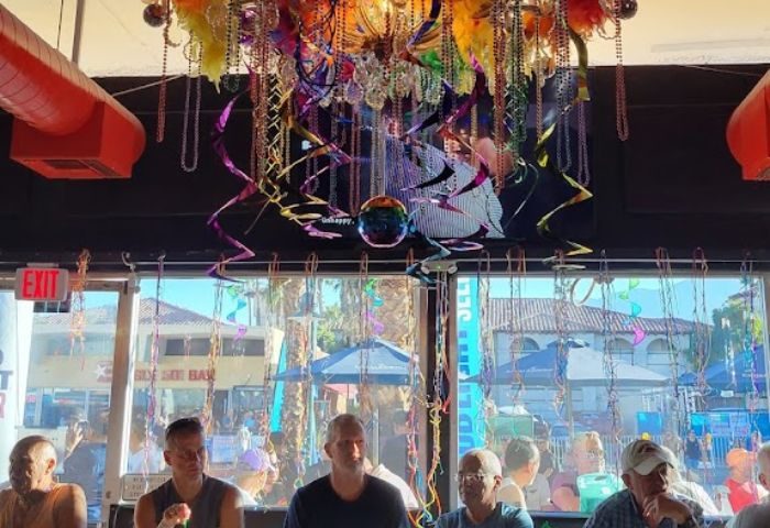 Inside Streetbar, a gay bar: Men sit at the bar under colorful decorations. A rainbow disco ball hangs from the ceiling. Gay travel advice.