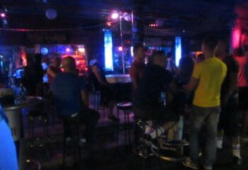 Inside Strong gay cruise club in Gran Canaria. Men at the bar under neon lights. Gay travel advice.