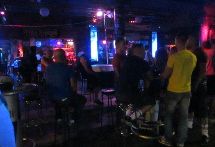 Inside Strong gay cruise club in Gran Canaria. Men at the bar under neon lights. Gay travel advice.
