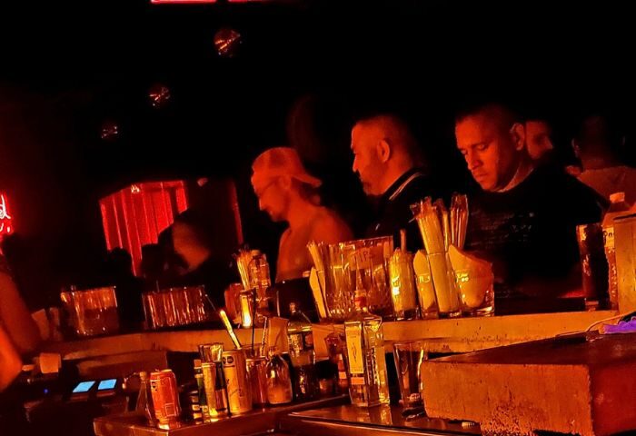 Studs Bear Bar, a gay place in Puerto Vallarta. Men at the bar in a dimly lit, red-toned gay bar. Nightlife scene.